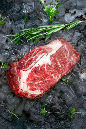 Raw fresh rib eye beef steak on ice with herbs and rosemaryの写真素材