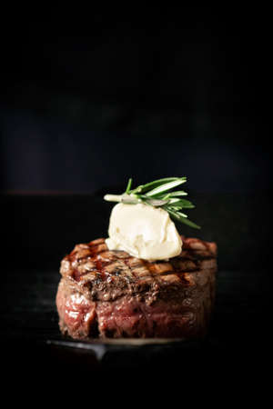 Grilled beef Tenderloin steak in a pan with butter on a dark background