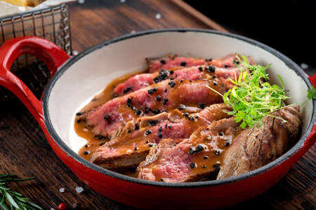 Sliced tenderloin medium rare steak with sauce on a plate, beef dish on a wooden Boardの写真素材