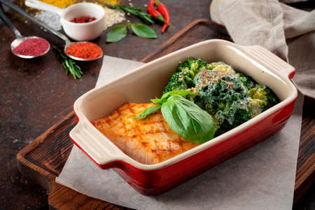 Baked salmon fillet with broccoli on a wooden table with spices, a recipe for a healthy dinnerの写真素材