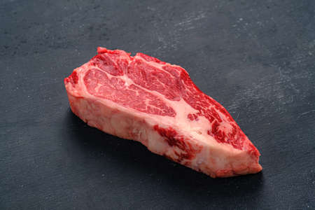 Fresh raw meat of Prime quality chuck steak. Dark background. Side view
