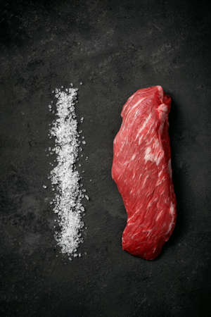 Raw beef tenderloin or bavet steak with salt on a dark stone backgroundの写真素材