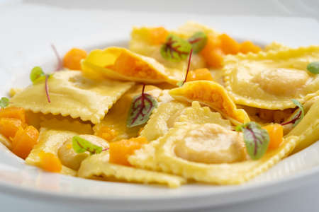 Cooked ravioli with pumpkin and Parmesan on a white plate close upの写真素材