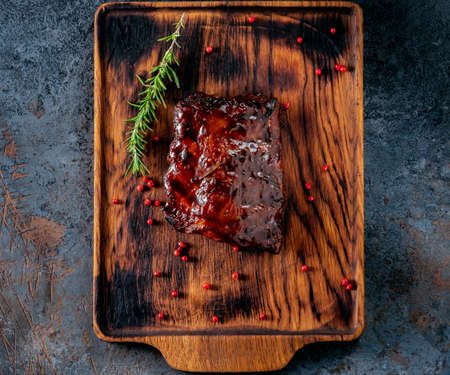 Grilled pork ribs with barbecue sauce on a wooden Board with spices and rosemary, top viewの写真素材