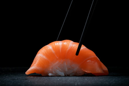 Sushi nigiri with salmon and chopsticks with dark stone background, Japanese food for restaurant menuの写真素材