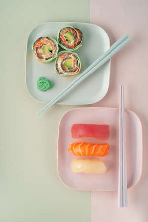Set of sushi nigiri and rolls with cucumber and salmon on a plate with chopsticks on a green backgroundの写真素材