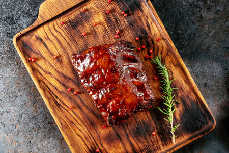 Grilled pork ribs with barbecue sauce on a wooden Board with spices and rosemary, top viewの写真素材