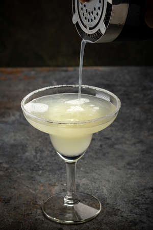 Classic tequila Margarita cocktail is poured into a glass from a shakerの写真素材