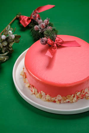 christmas cake is decorated with a ribbon and a fir branch on a green background.の写真素材