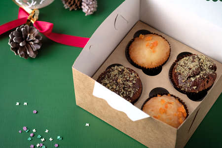 Cupcakes with chocolate, pistachios and orange in a gift box on the table. Desserts in a cardboard...