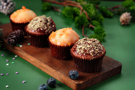 Chocolate and orange cupcakes on a wooden board with Christmas decorations. Sweet muffins on the tableの写真素材