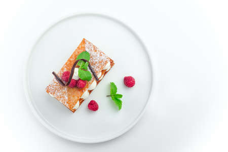 Mille feuille dessert with raspberry and whipped sour cream on a white plate, isolated on white