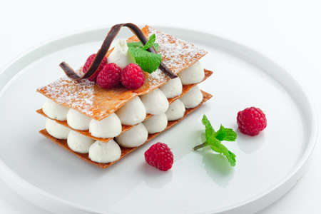 Classic raspberry mille feuille dessert with whipped sour cream on a white plate