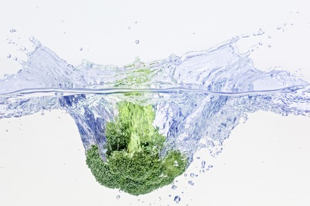 Green broccoli falling in water on white with air bubblesの写真素材