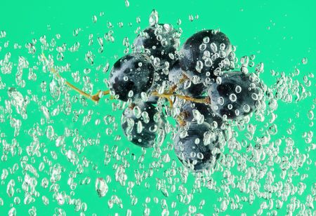 Bunch of grapes floating in green water with air bubbles
