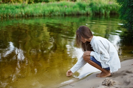 Beautiful young woman building sand castle on the lake coastの写真素材