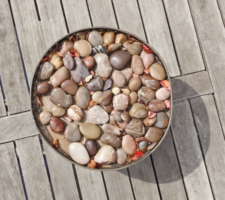 Vase with pebble stone decor on old gray wooden tableの写真素材