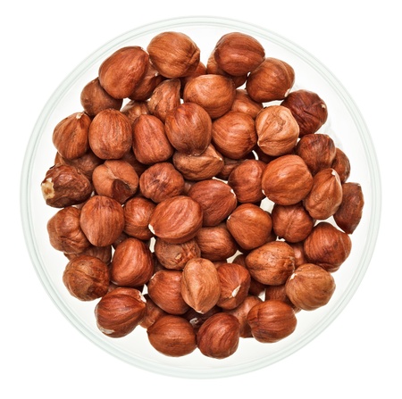 Unshelled hazel nuts in a glass bowl isolated on white