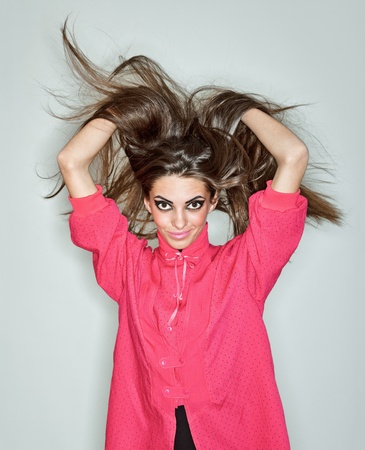 Young brunette lady dressed in pink blouse playing with long hairs, ring flash studio portrait on whiteの写真素材