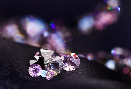Diamond (small purple jewel) stones heap over black silk cloth backgroundの写真素材