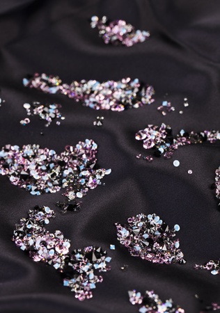 Diamond (small purple jewel) stones heap over black silk cloth backgroundの写真素材