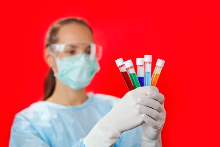 Doctor (woman) analyzing medical test tubes on red background