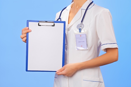 Doctor with copyspaced clipboard waist-high portrait on blueの写真素材