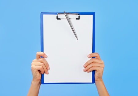 Clipboard in female hands on blue backgroundの写真素材