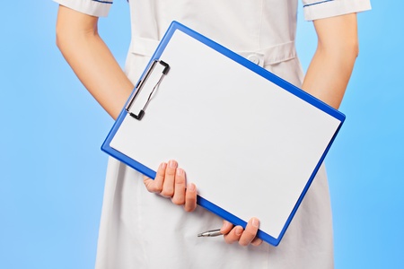 Doctor with copyspaced clipboard waist-high portrait on blueの写真素材