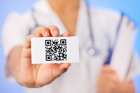 Doctor holding business card with health care QR code on blueの写真素材