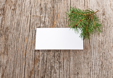 Wooden background with empty white card and fir branchの写真素材