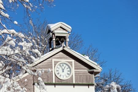 Old wooden snow covered chapel with clockの写真素材