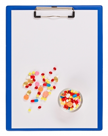 Blue medical clipboard with pills and tablets isolated on whiteの写真素材