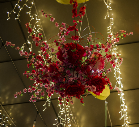 A beautiful red flower arrangement hanging from the roof, with amazing yellow lighting.の写真素材
