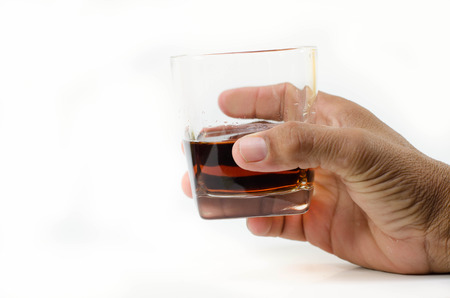 Glass of whisky in hand isolated on a whiteの写真素材