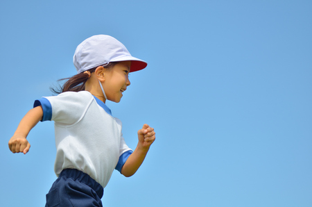 Girl in blue sky gym clothes, red white hatの写真素材