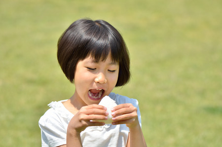 Girl eating rice ballsの写真素材