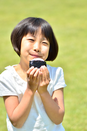 Girl eating rice ballsの写真素材