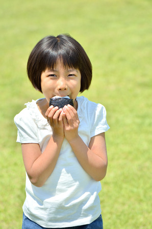 Girl eating rice ballsの写真素材