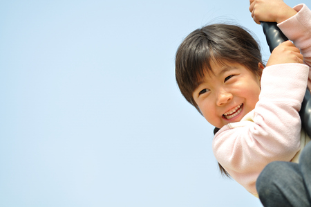 A girl playing at the playground in the Parkの写真素材