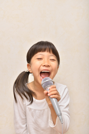 Girl singing in a microphoneの写真素材