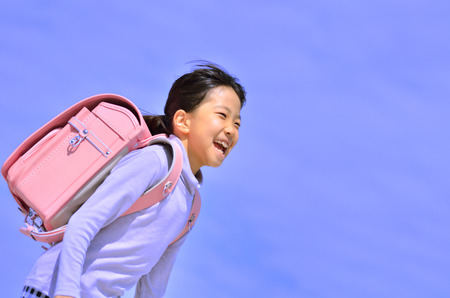Elementary school children running in the blue skyの写真素材