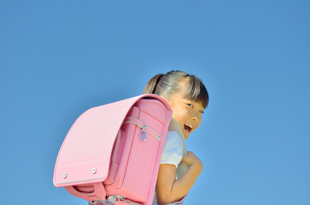 Elementary school children laughing in the blue skyの写真素材