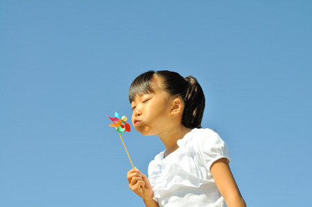 Girl blowing pinwheelの写真素材