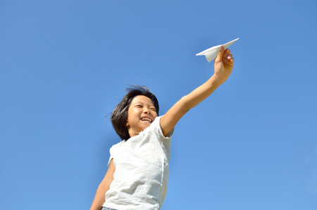 Girls fly paper plane in the blue skyの写真素材