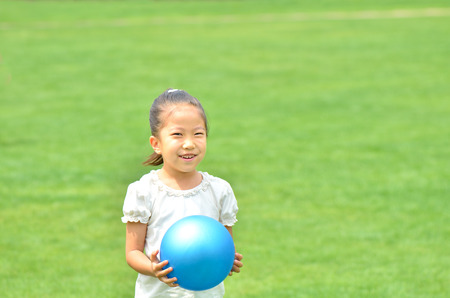 Girls play with ball in the grasslandの写真素材