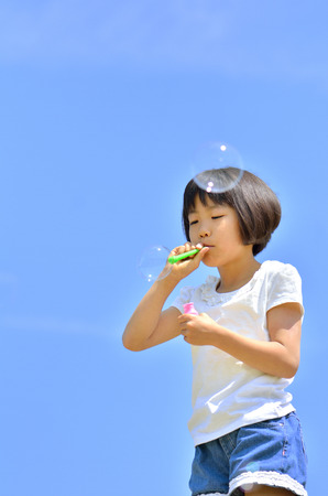 Girls blowing soap bubbles in the blue skyの写真素材
