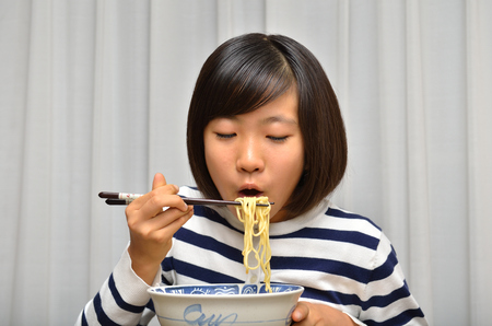 Girl's eating chinese noodleの写真素材