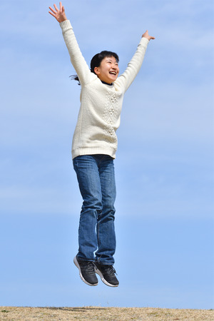 Japanese girl jumping in the blue skyの写真素材