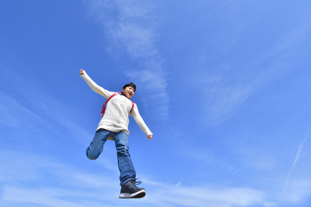 Japanese elementary school girl jumping in the blue skyの写真素材